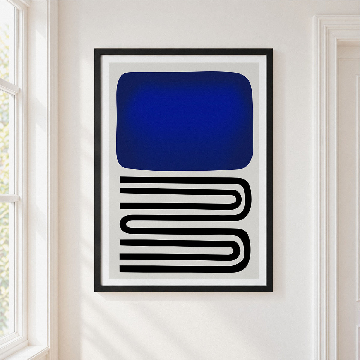 Framed abstract wall art hanging on a white wall, featuring a large deep blue rounded rectangle above black parallel curved lines on a white background.
