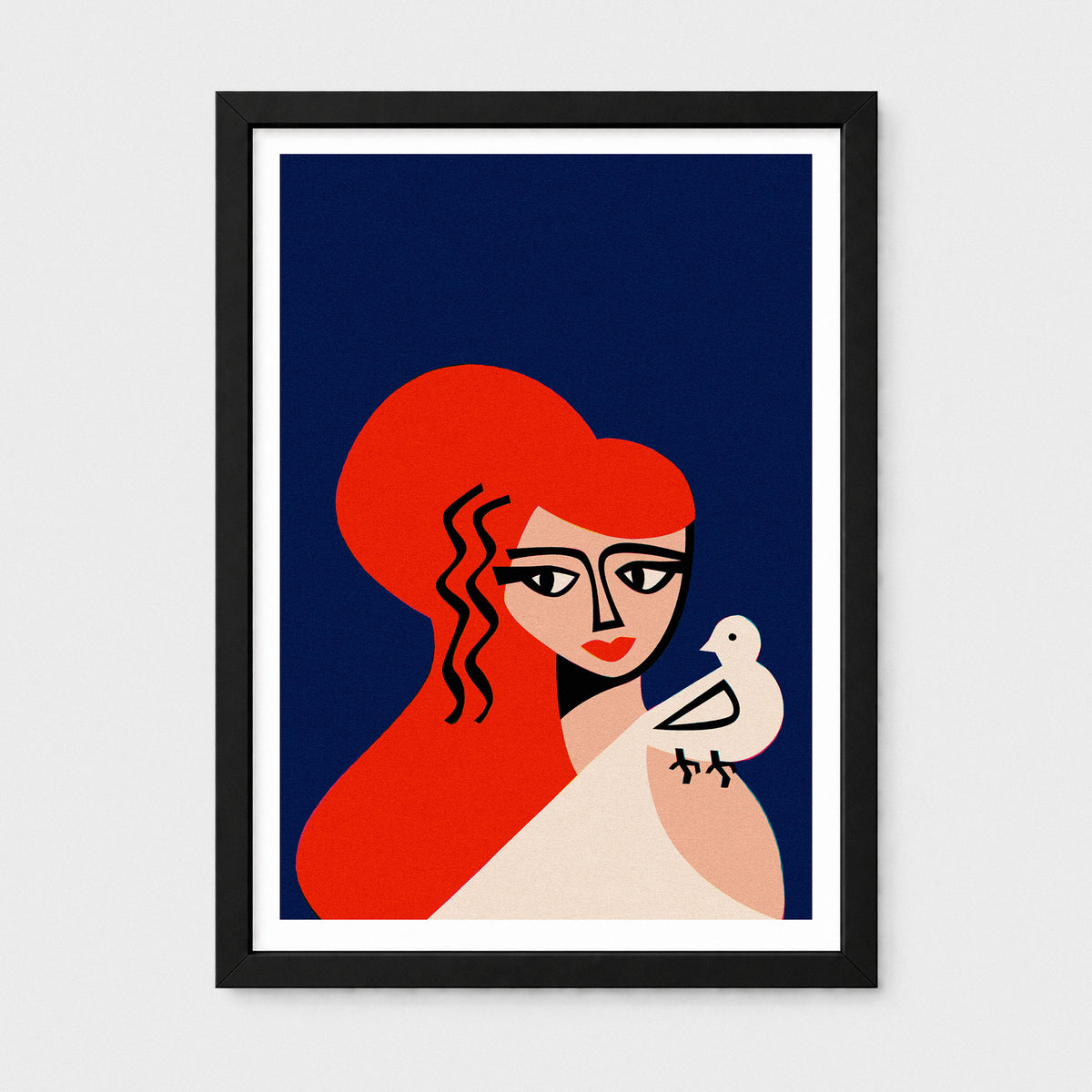 A framed art print featuring a stylized illustration of a Aphrodite with vibrant red hair and a white bird on her shoulder, set against a dark navy blue background. The print is framed in a black frame with a white mat, hanging on a light gray wall.