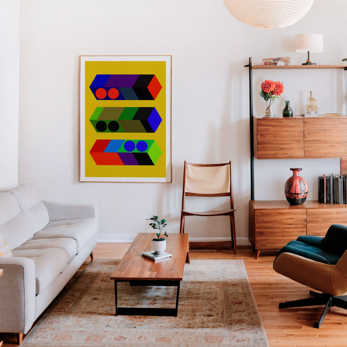 A framed abstract geometric wall art print hangs on a white wall in a modern living room with a light gray sofa, wooden coffee table, chair, and shelving.