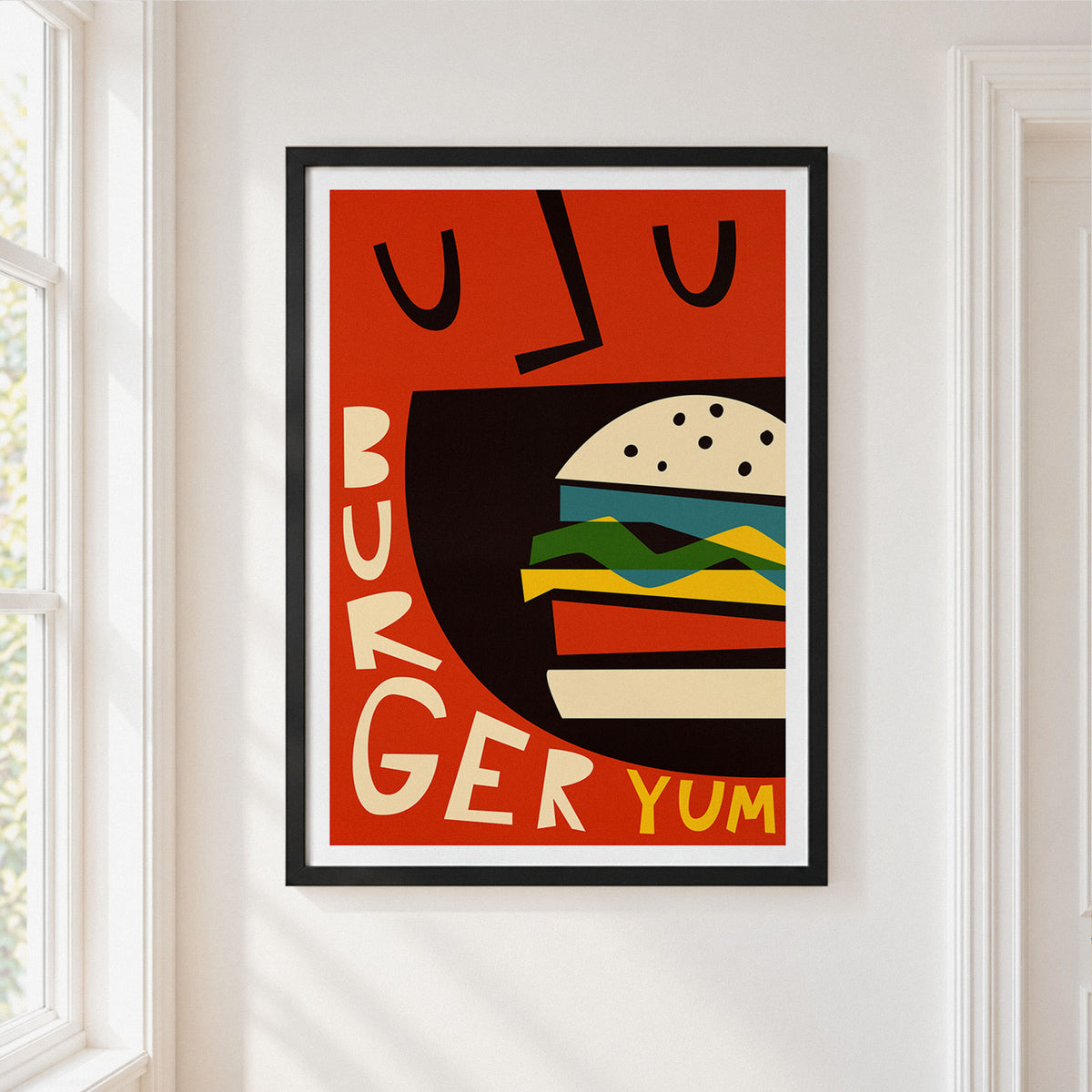 A framed retro-style poster featuring a stylized burger illustration with the words 'BURGER YUM' on a warm red-orange background, hung on a white wall next to a window.