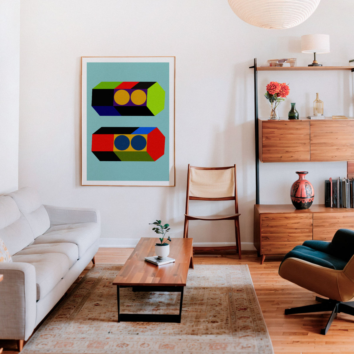 A framed abstract geometric wall art print hangs on a white wall in a modern living room with a light gray sofa, wooden coffee table, chair, and shelving.