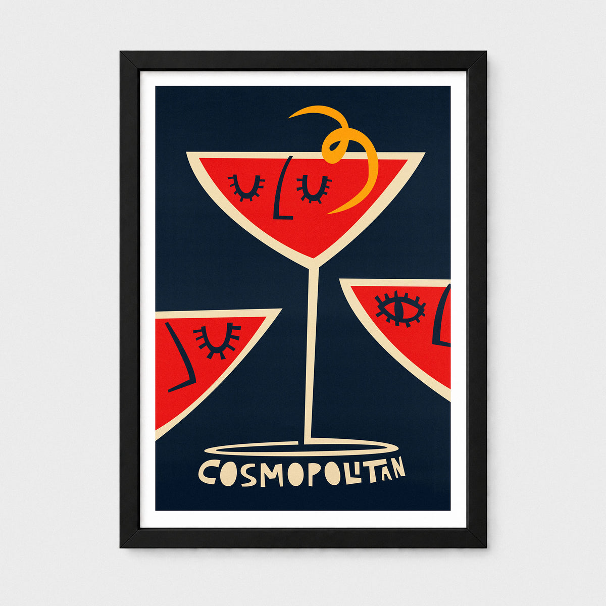 Framed art print featuring three red cocktail martini glasses with stylized faces and a yellow twist on a dark navy background, with the word 'COSMOPOLITAN' at the bottom. The print is framed in black with a white mat against a light gray wall.