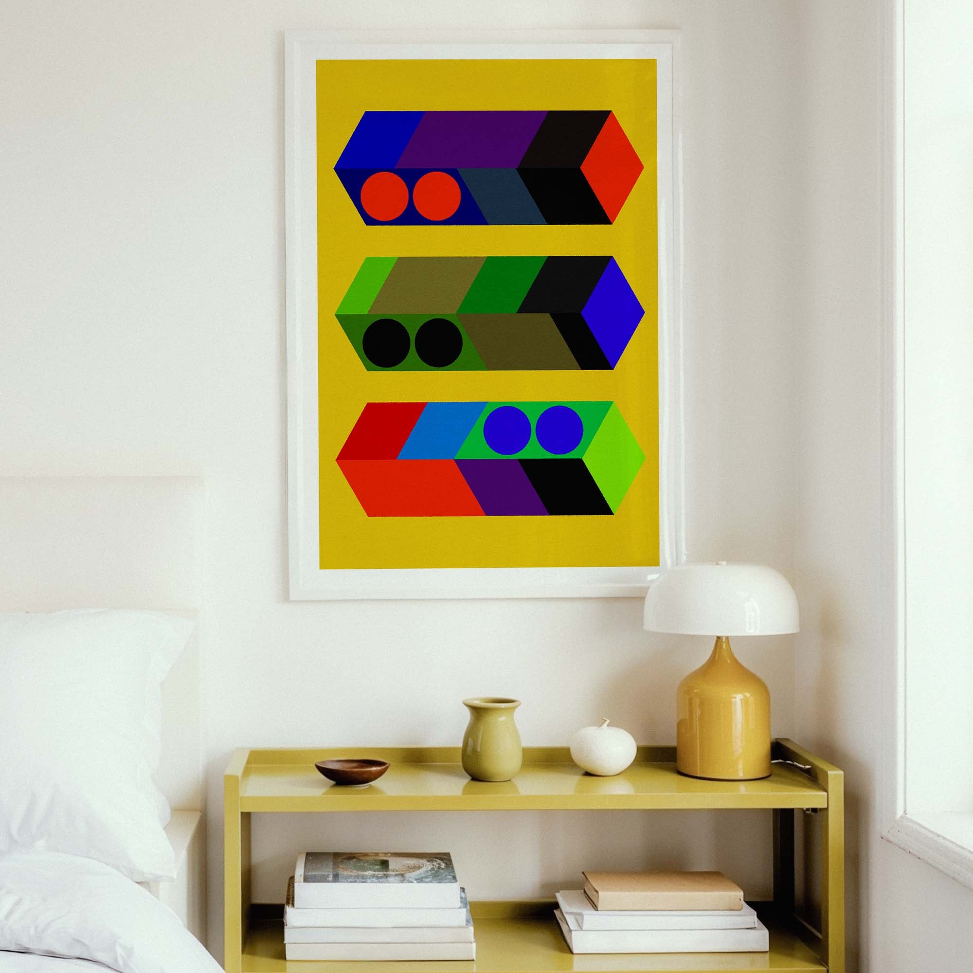 Colorful abstract art piece on a wall above a wooden shelf with books and a lamp.