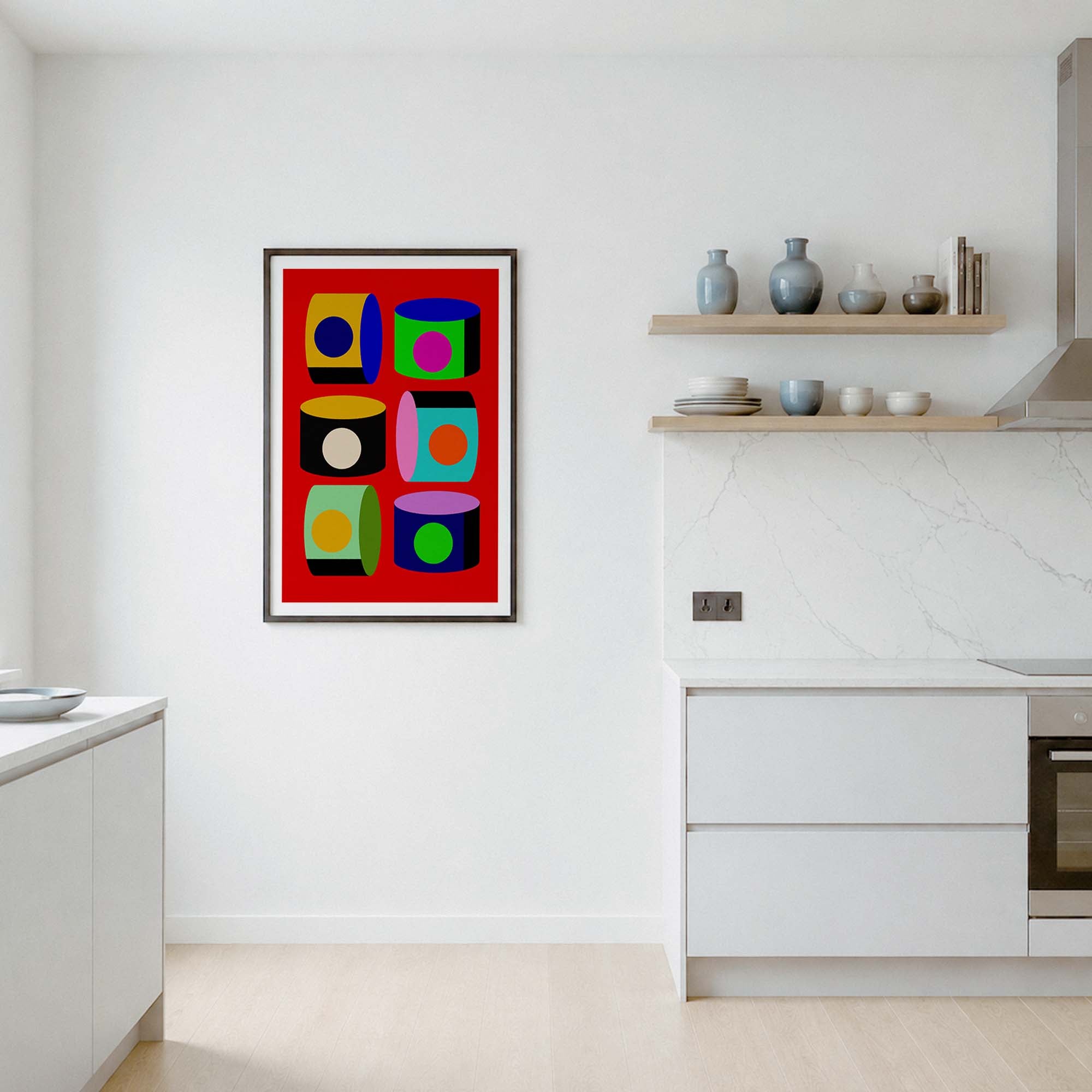 A framed abstract geometric art print with a bold red background and colorful square blocks hangs on a white wall in a modern kitchen setting.