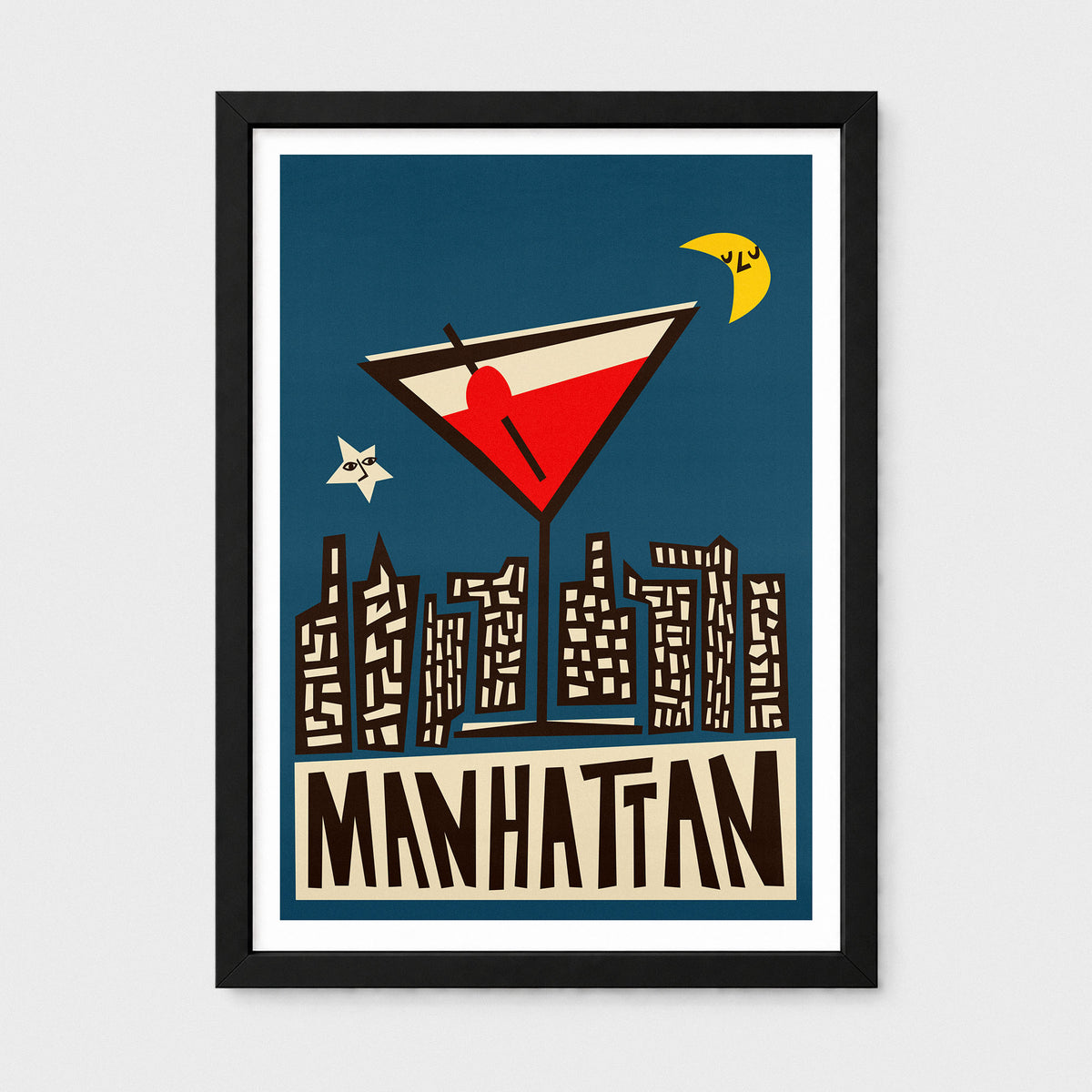 A framed art print featuring a stylized illustration of a martini glass above a Manhattan skyline, with a dark blue background, cream buildings, brown lettering reading "MANHATTAN," and a black frame on a light gray wall.