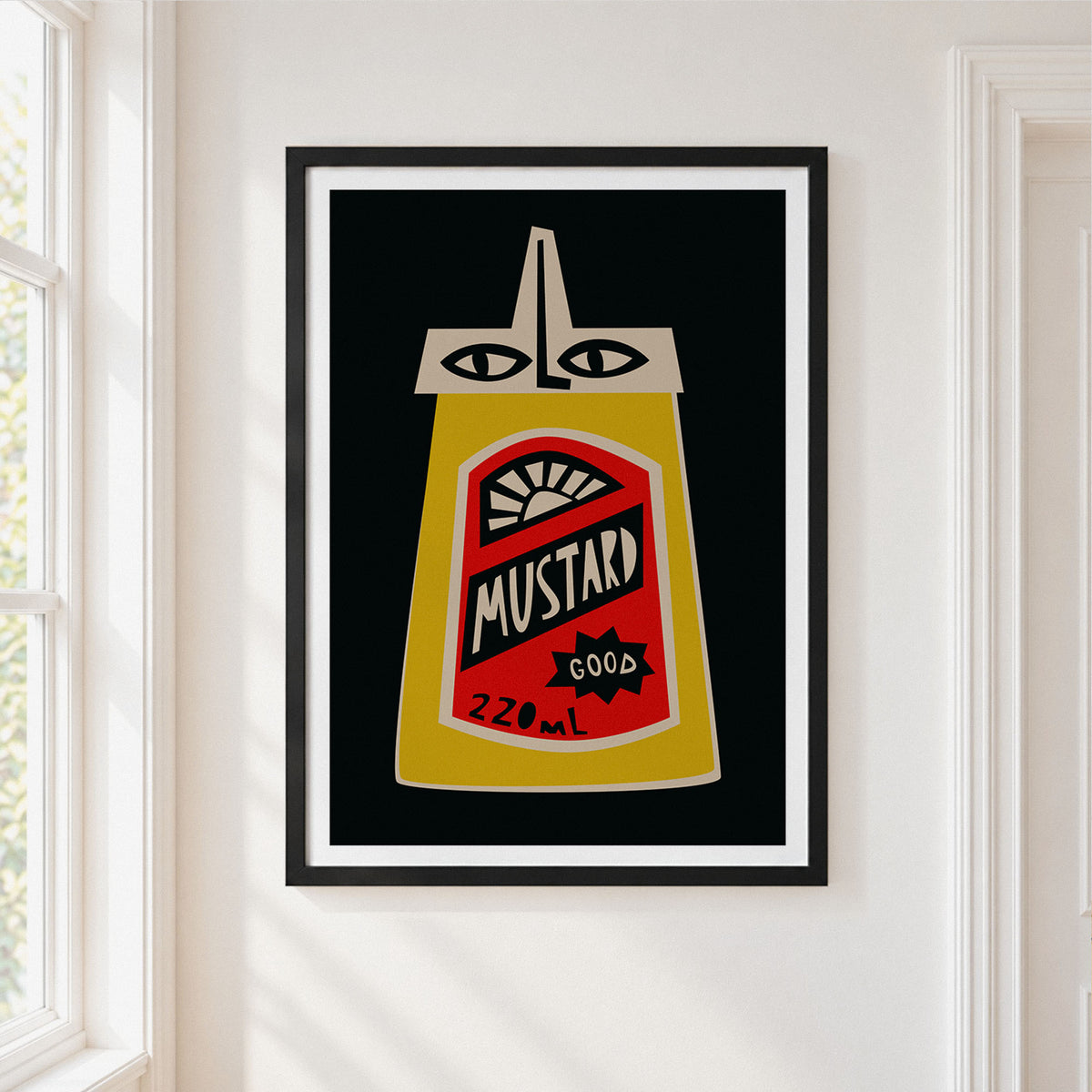 A framed pop-art print of a mustard bottle with a stylized face, displayed on a white wall next to a window.