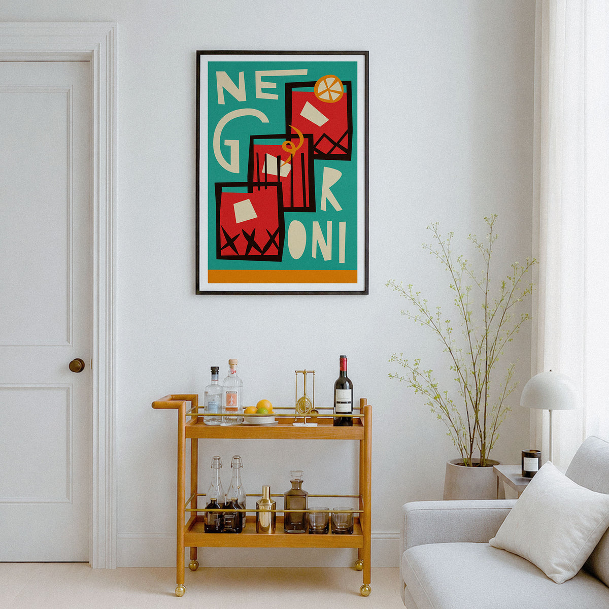 A framed abstract art print featuring the words 'NEGRONI' in bold red, black, white, and yellow geometric shapes over a teal background, hanging on a white wall above a gold bar cart in a modern living room setting.
