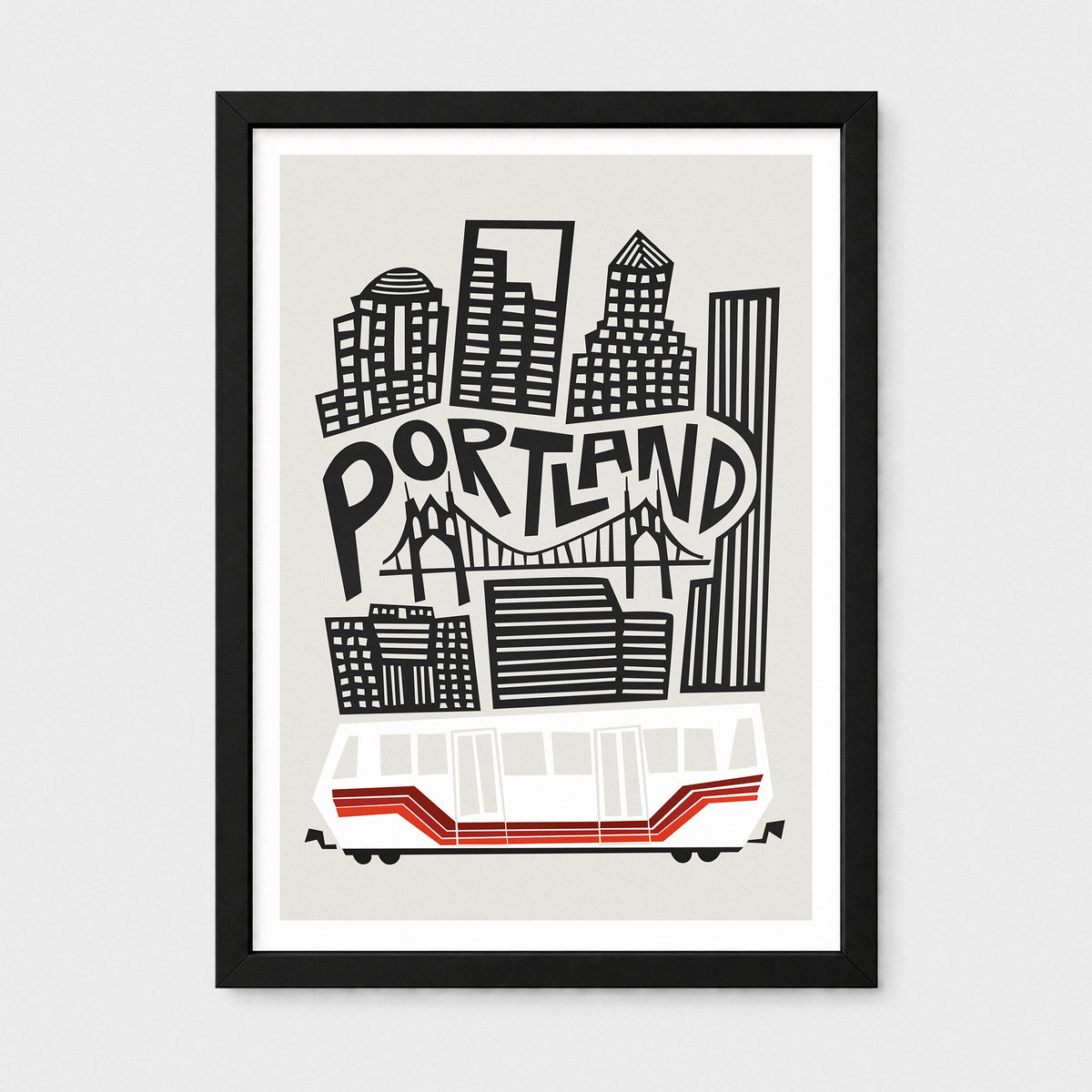 Framed Portland cityscape wall art print with black buildings, a bridge, the word 'PORTLAND,' and a white cable car with red stripes, shown in a black frame against a light gray background.