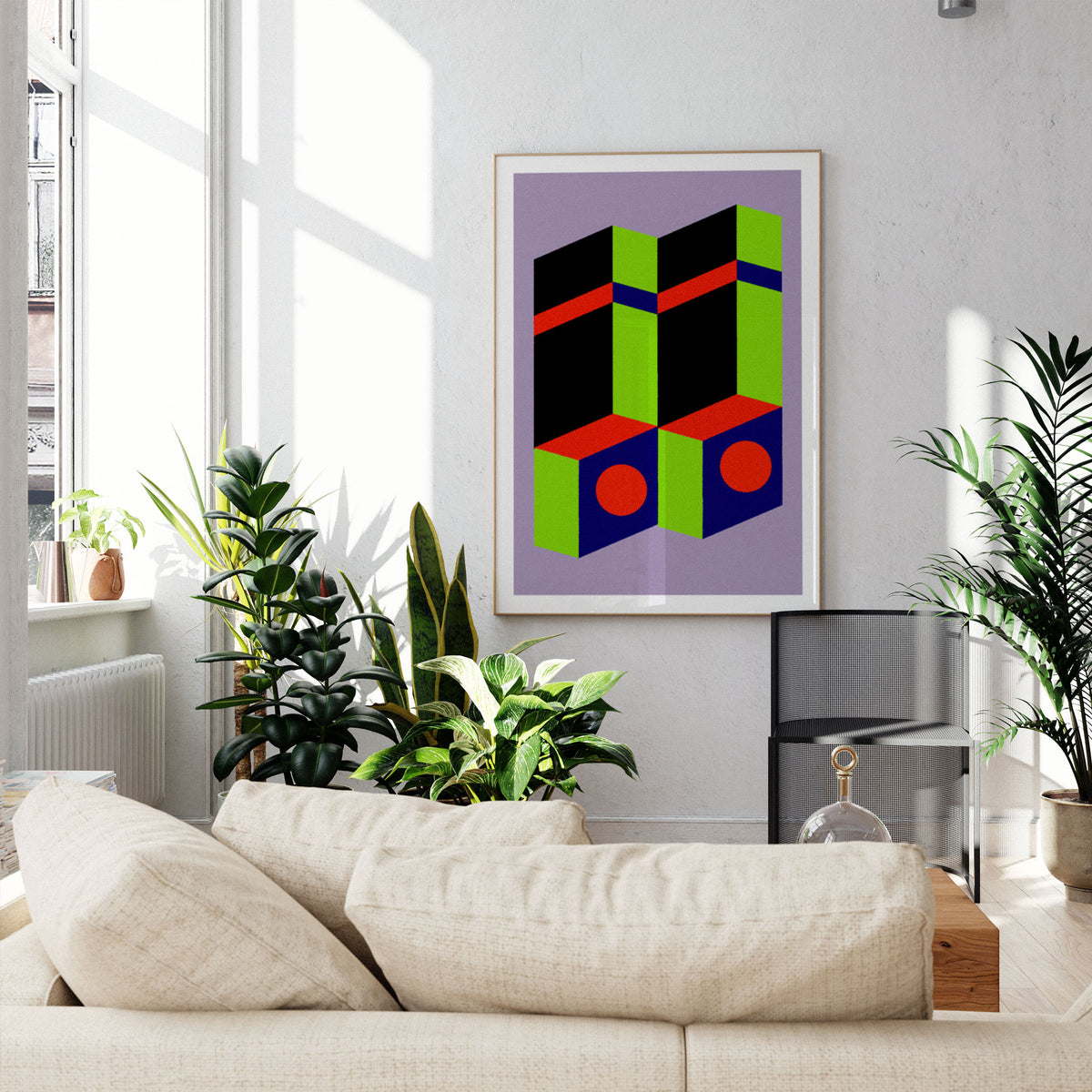 A framed abstract geometric art print with bold green, red, black, and blue shapes on a lavender background, hanging on a light gray wall above a beige sofa in a sunlit living room with potted plants.