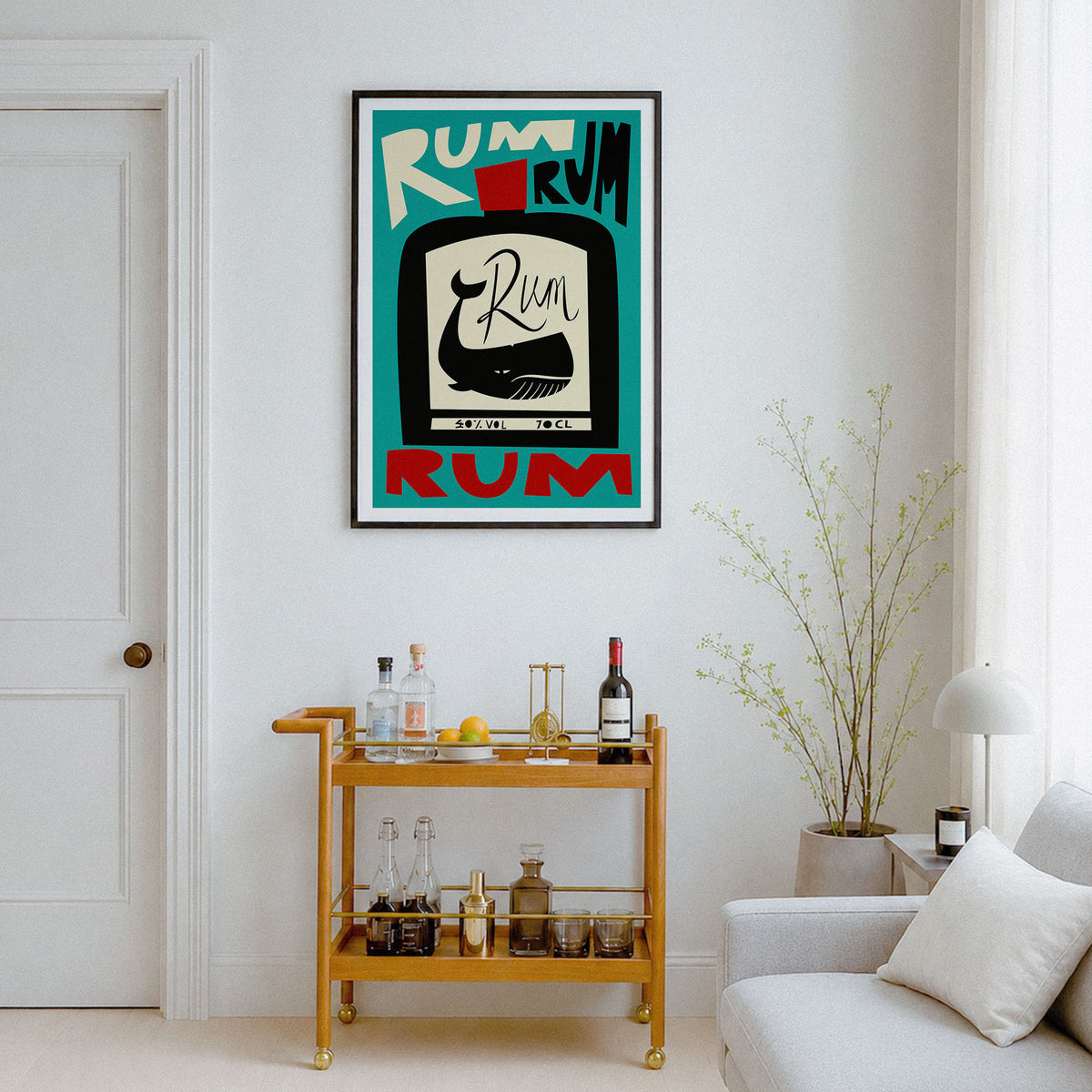 A framed art print featuring a retro television screen with a black-and-white whale illustration and the word 'RUM' in bold teal, red, and cream lettering, displayed on a white wall above a wooden bar cart in a styled living room.