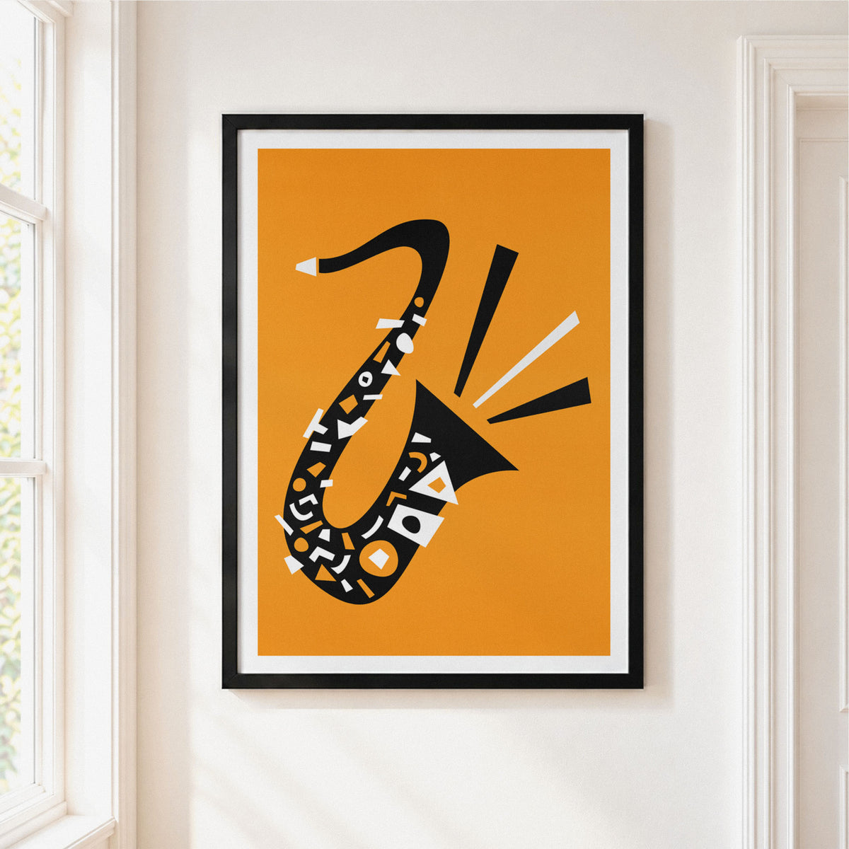 A framed minimalist art print of a saxophone on a warm orange background, hung on a white wall next to a window.