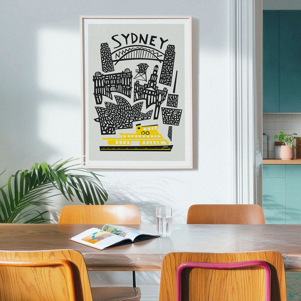 A framed Sydney travel art print featuring black line drawings of landmarks and a bright yellow ferry on a light gray background, hanging on a white wall above a wooden dining table with chairs in a modern kitchen setting.