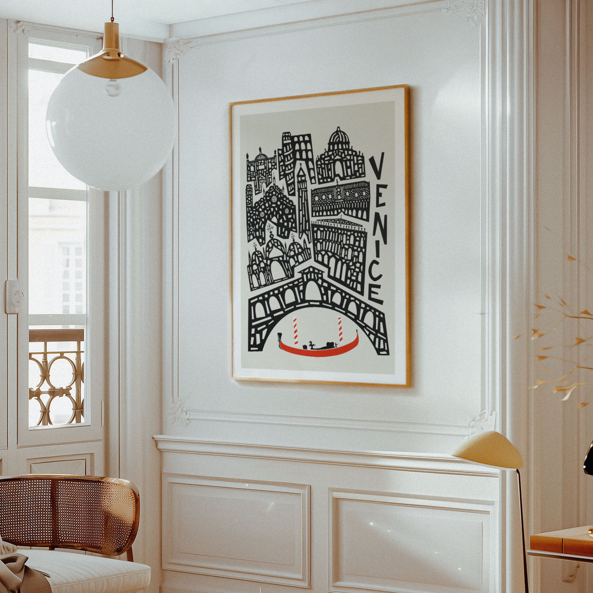 A framed Venice cityscape art print with black architectural line art, a red gondola, and the word 'VENICE' on a light background, hanging on a white paneled wall in a bright interior room.