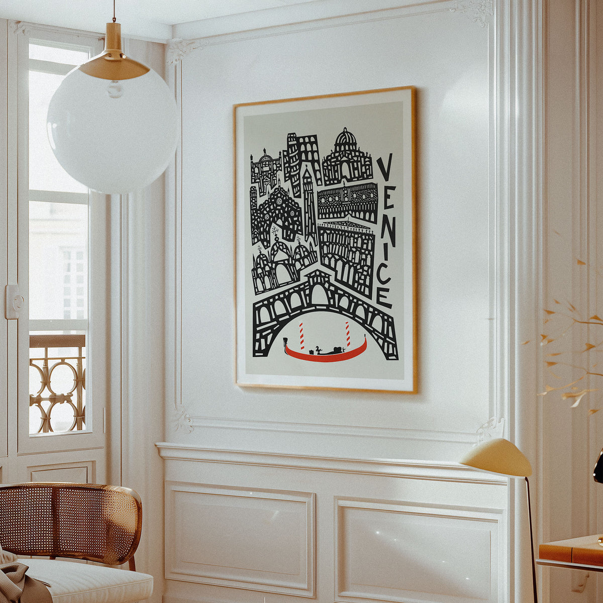 A framed Venice cityscape art print with black architectural line art, a red gondola, and the word 'VENICE' on a light background, hanging on a white paneled wall in a bright interior room.