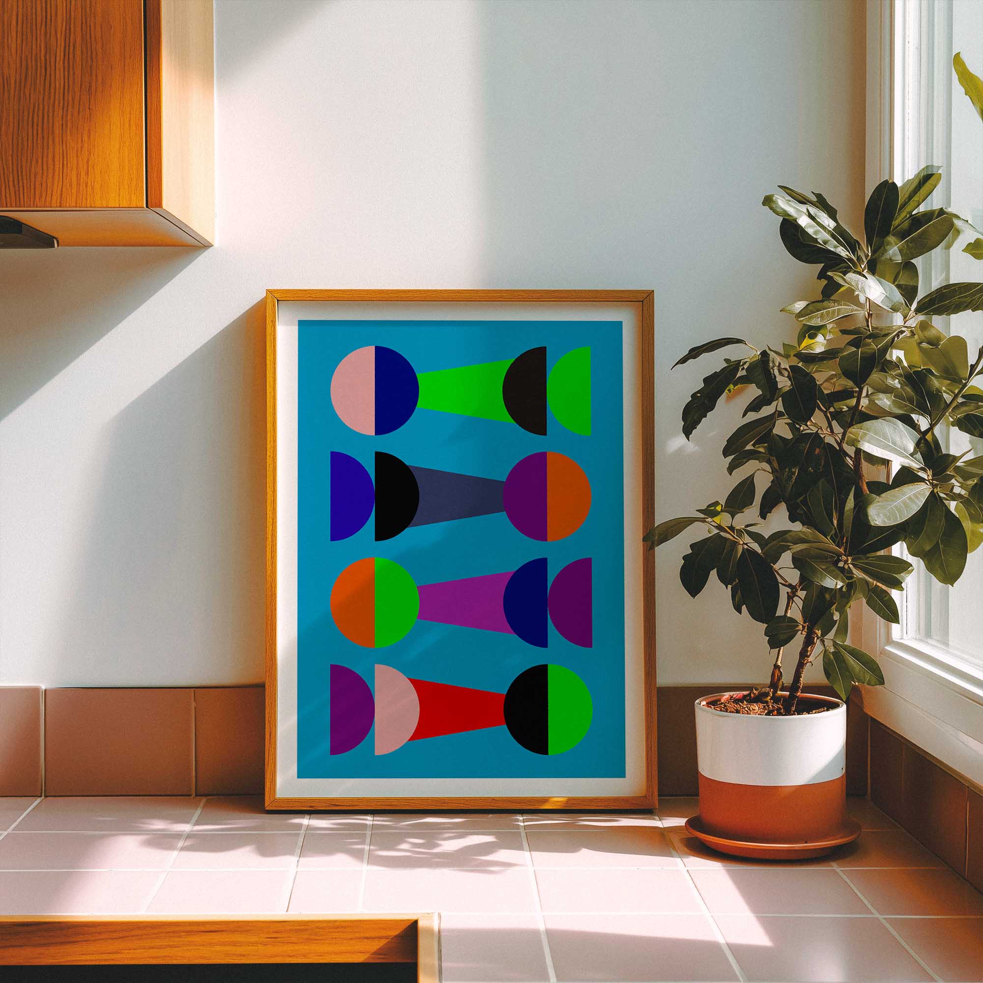 Framed abstract kitchen art print on a wall with a plant next to it