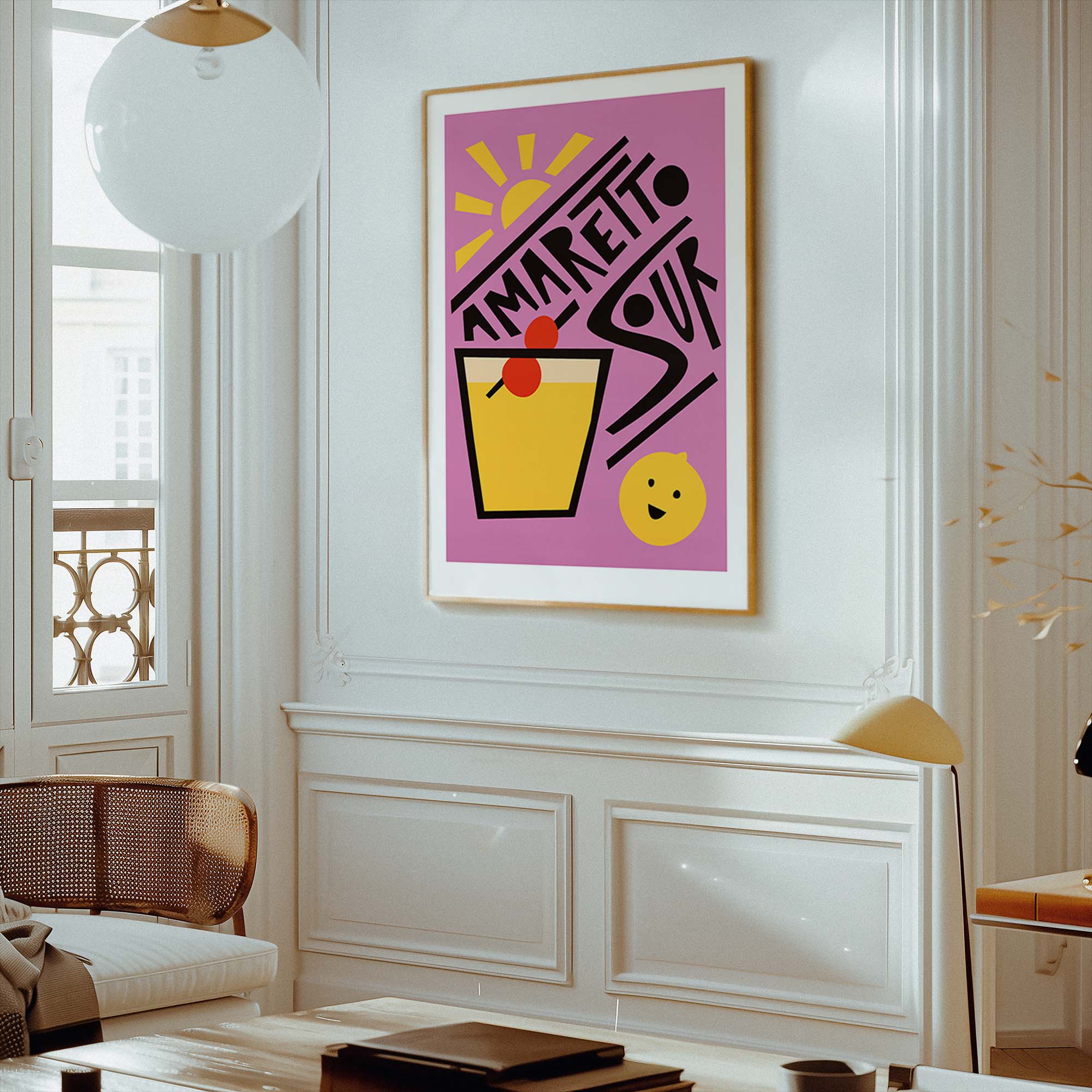 A framed art print featuring a colorful retro-style cocktail illustration with the text 'AMARETTO SOUR' on a pink background, displayed on a white wall in a modern, elegant room.