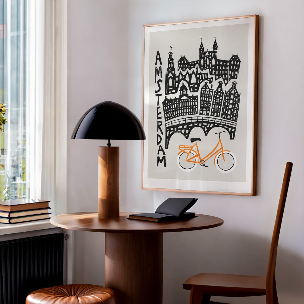 Framed Amsterdam illustration displayed above a desk in a cosy reading nook, creating a creative and relaxed European interior vibe.