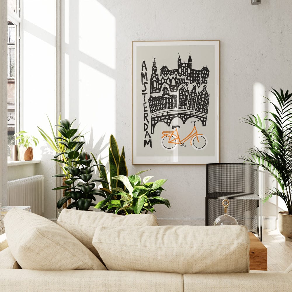 Amsterdam art print framed in a bright, plant-filled living space, adding playful architectural charm and graphic contrast to the room.
