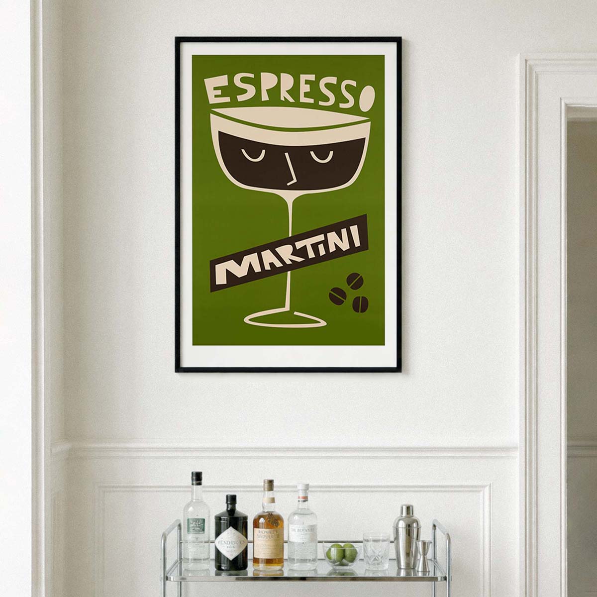 A framed vintage-style wall art print featuring an espresso martini glass illustration with the words 'ESPRESSO MARTINI' on a white wall above a bar shelf with bottles.