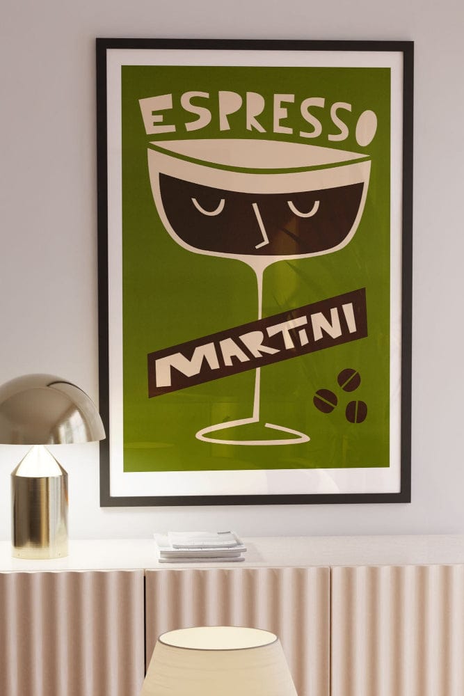 espresso martini illustration print in black frame above a stylish sideboard with brass lamp