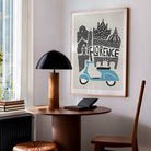 Framed Florence print styled in a cosy home workspace, showing how the iconic Italian landmarks and scooter lend character to a quiet, modern reading nook.