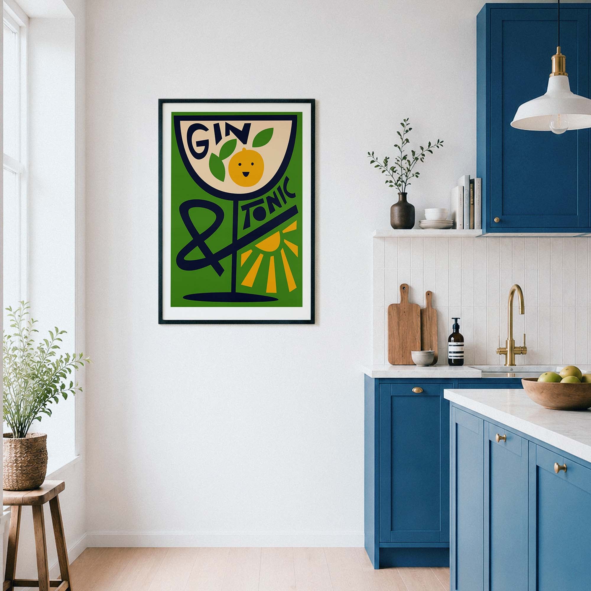 A framed vertical art print featuring a retro-style illustration of a gin glass with a lemon slice and the words 'GIN Tonic' on a green background, displayed on a white wall in a modern kitchen with blue cabinets.