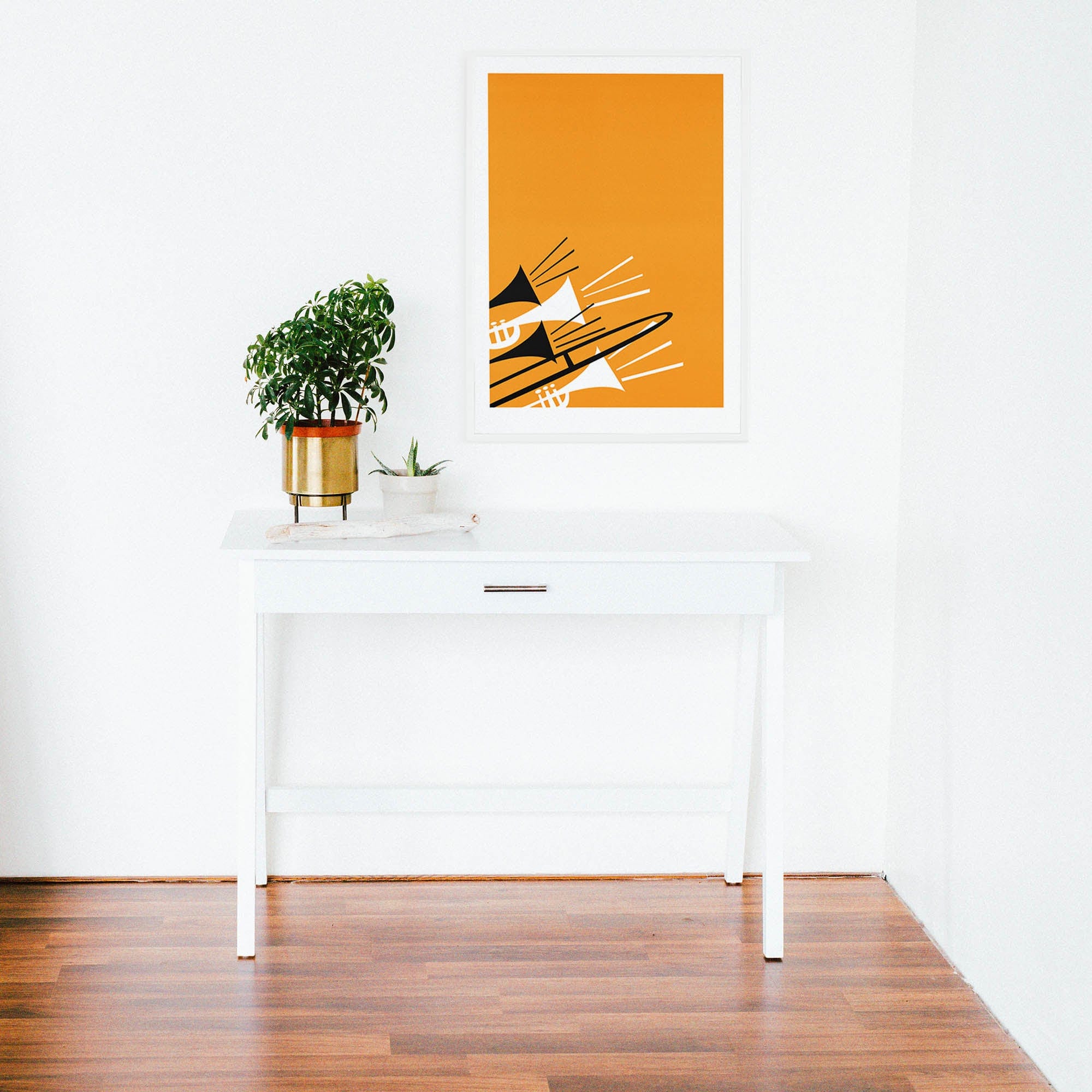 Brass instruments illustration displayed above a white desk with potted plants in a clean, modern interior