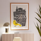 Norwich print framed above neutral shelf with soft lighting and tall indoor plant