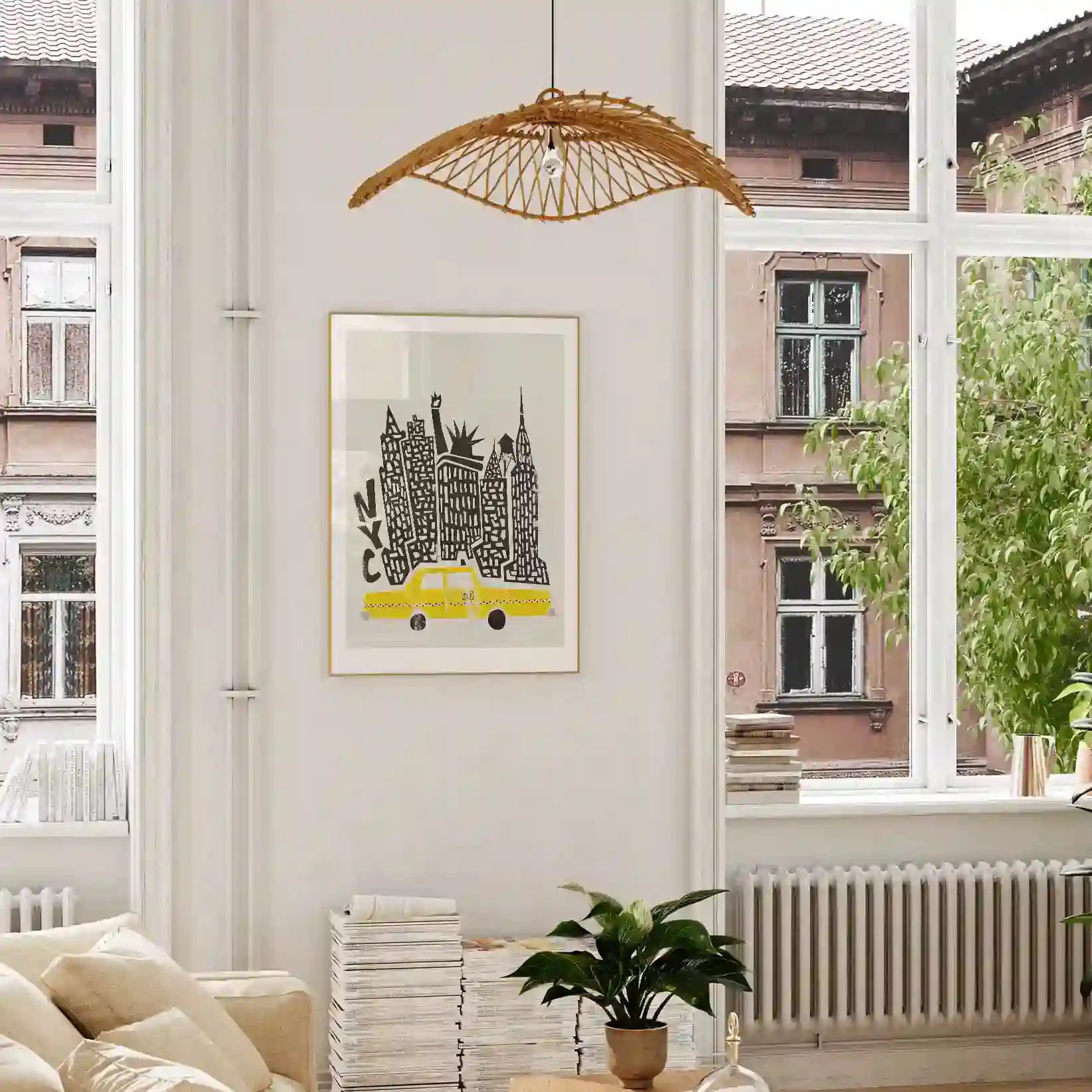 Framed NYC print featuring towering black buildings and a yellow cab, shown hanging in a bright, modern room with wood accents and leafy plants.