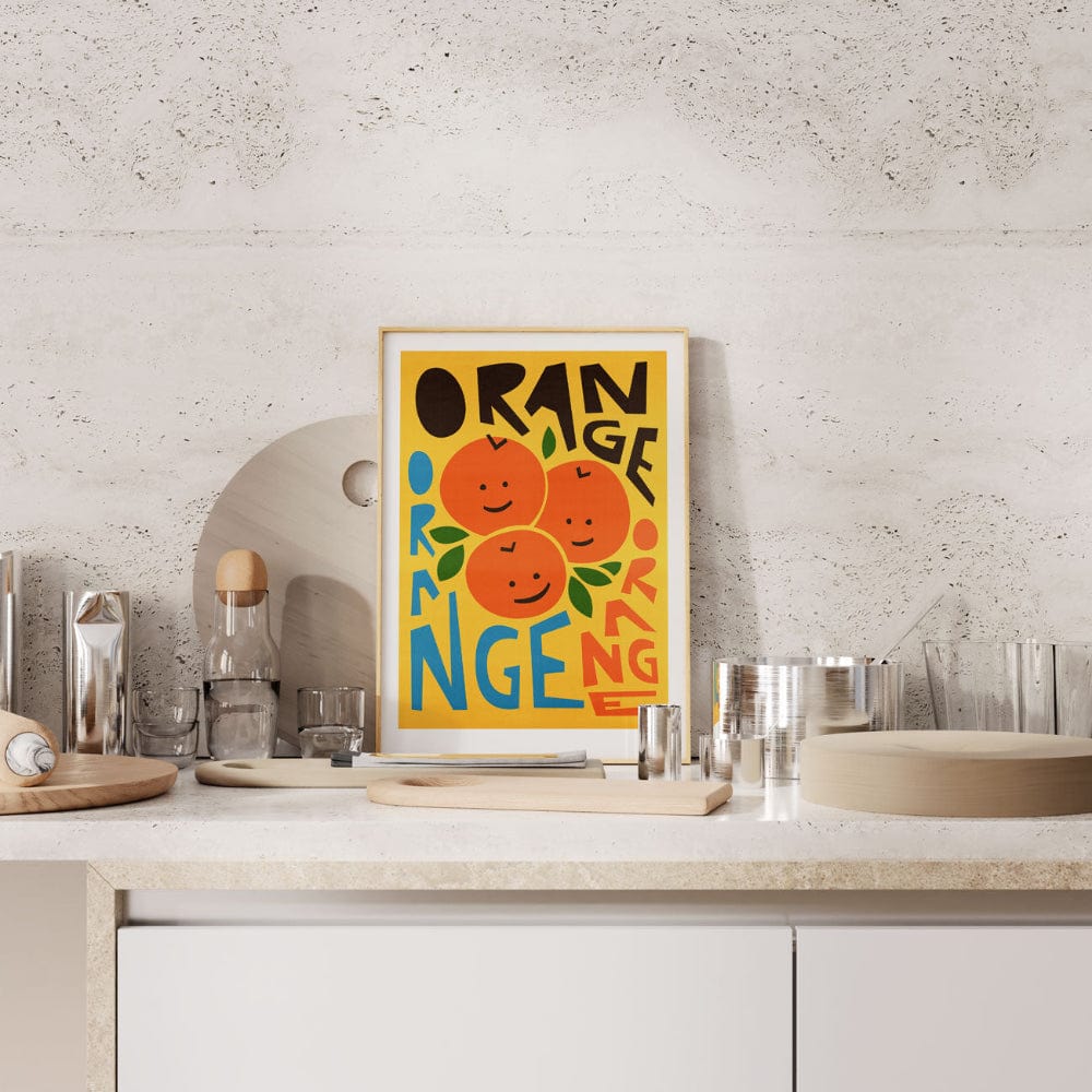 Orange-themed art print propped on a clean white benchtop in a modern home.