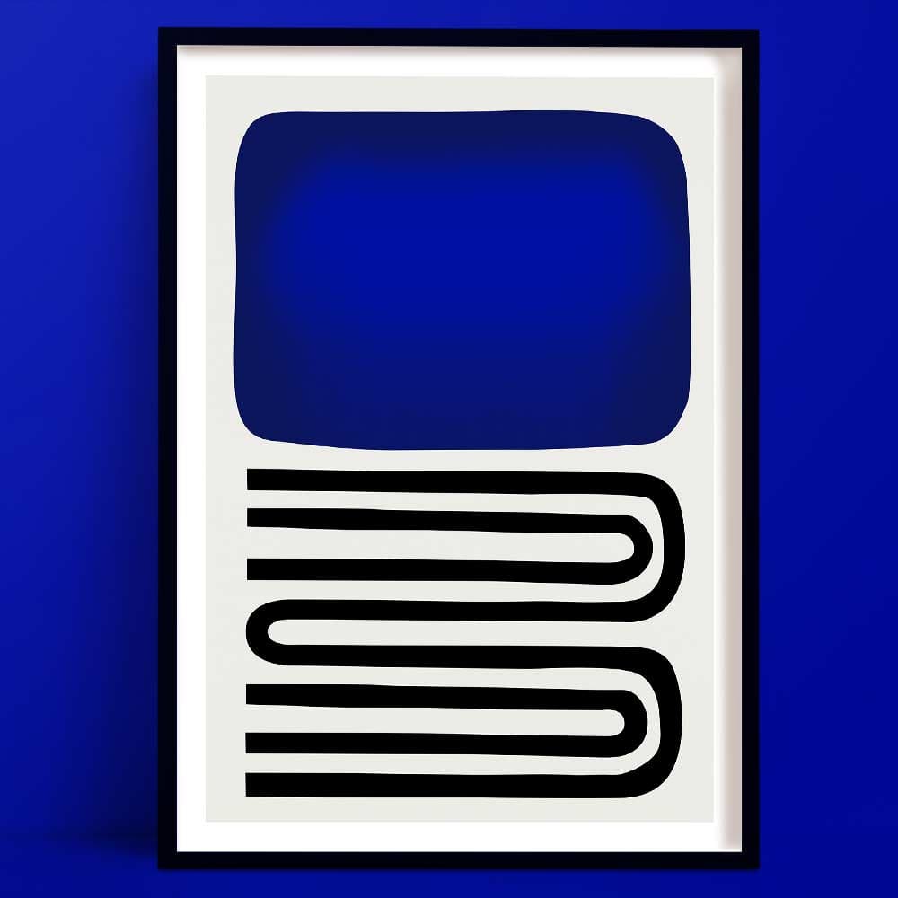 An out of the blue abstract art print, framed, with bold blue block and curved black lines, set against blue wall.