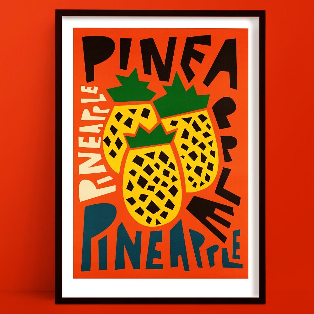 Pineapple print featuring two graphic pineapples surrounded by overlapping “PINEAPPLE” text in bold, varied lettering, framed on a vivid orange wall.