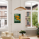 Pisces artwork framed above a low sofa in a bright room with high windows, indoor plants, and natural textures.