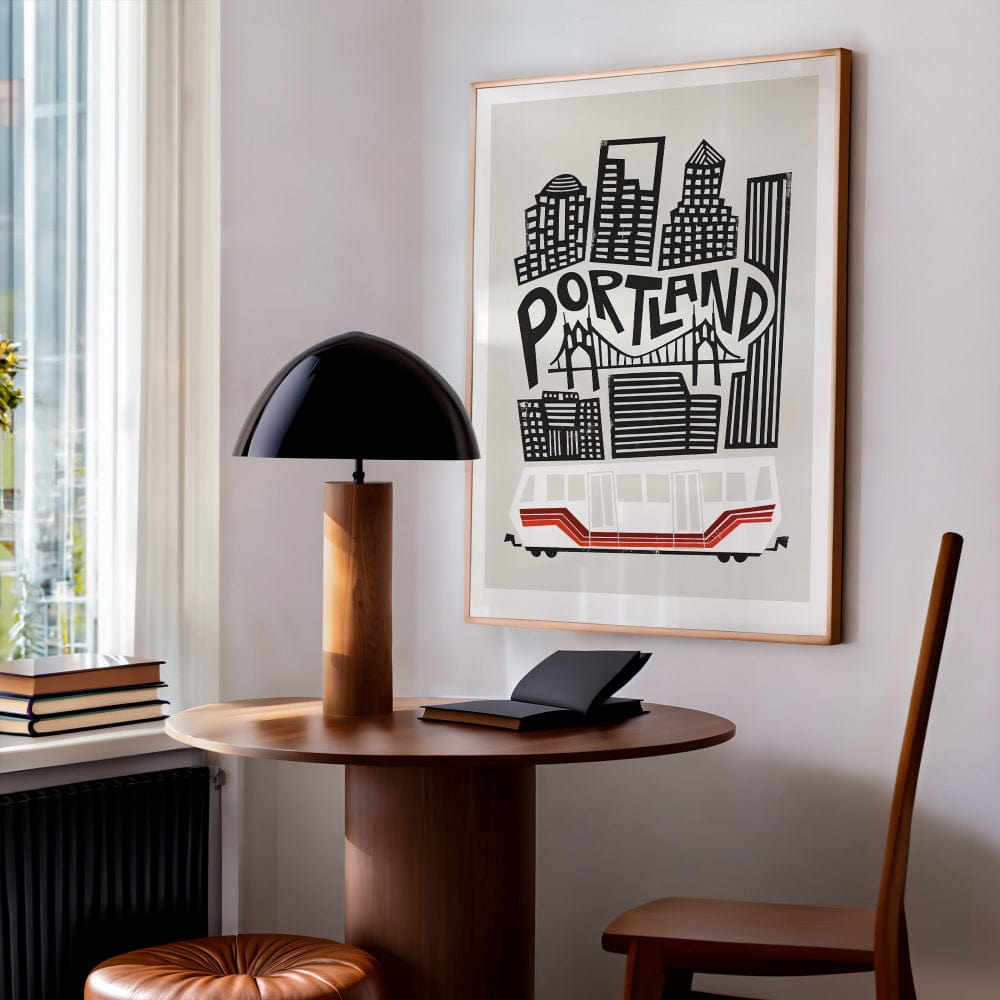 The Portland print framed and hung above a round table with a black lamp, showcasing the urban aesthetic of the design in a warm, styled interior.