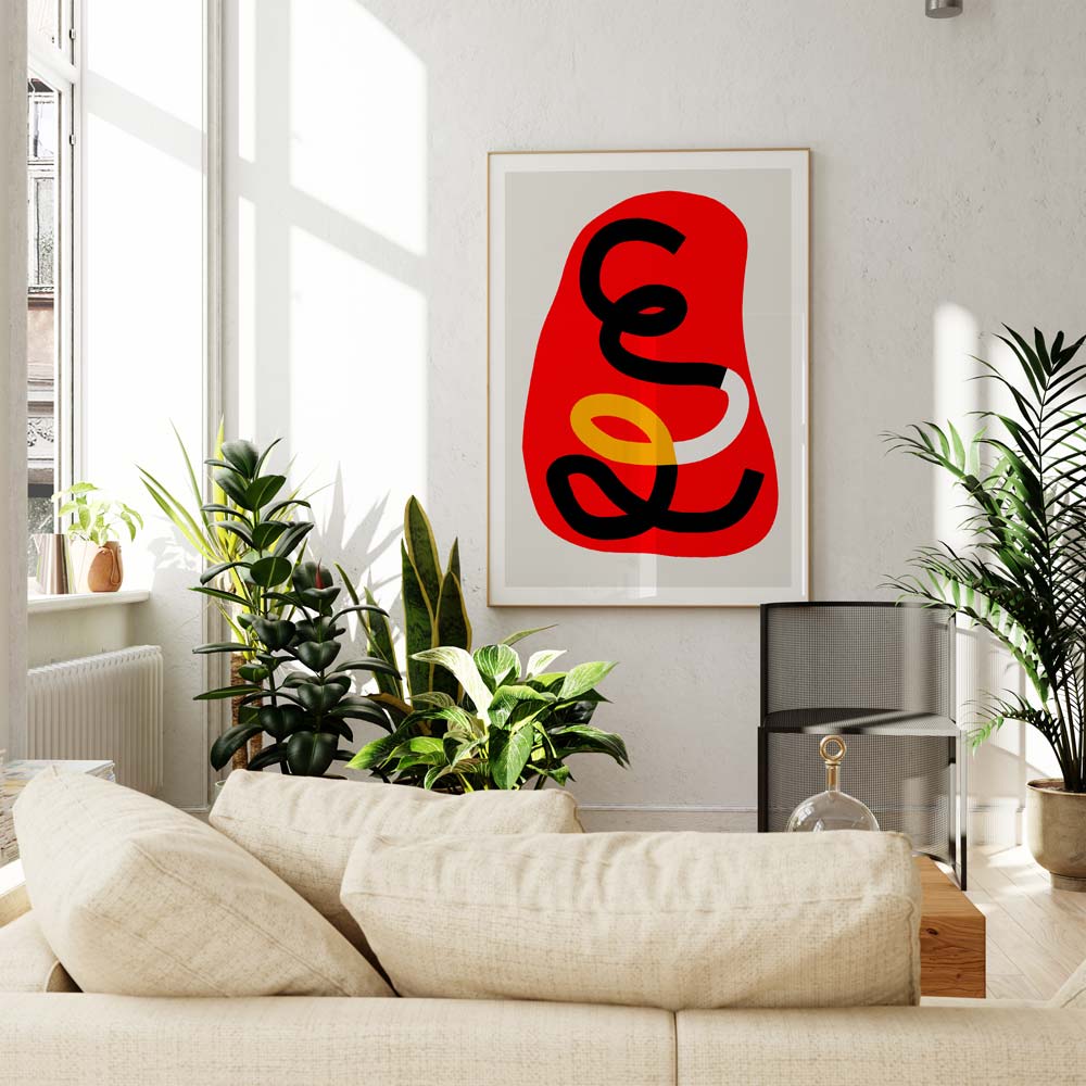 Abstract art print in red tones framed above cream sofa, styled with houseplants and soft light