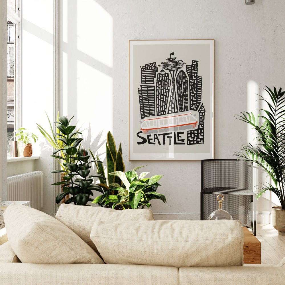 The Seattle print framed in a calm interior space, showing off its quirky illustration of stacked towers and the unmistakable silhouette of the Space Needle.
