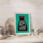 Soy Sauce print framed on a stone-textured kitchen shelf with small plates and cocktail glasses.
