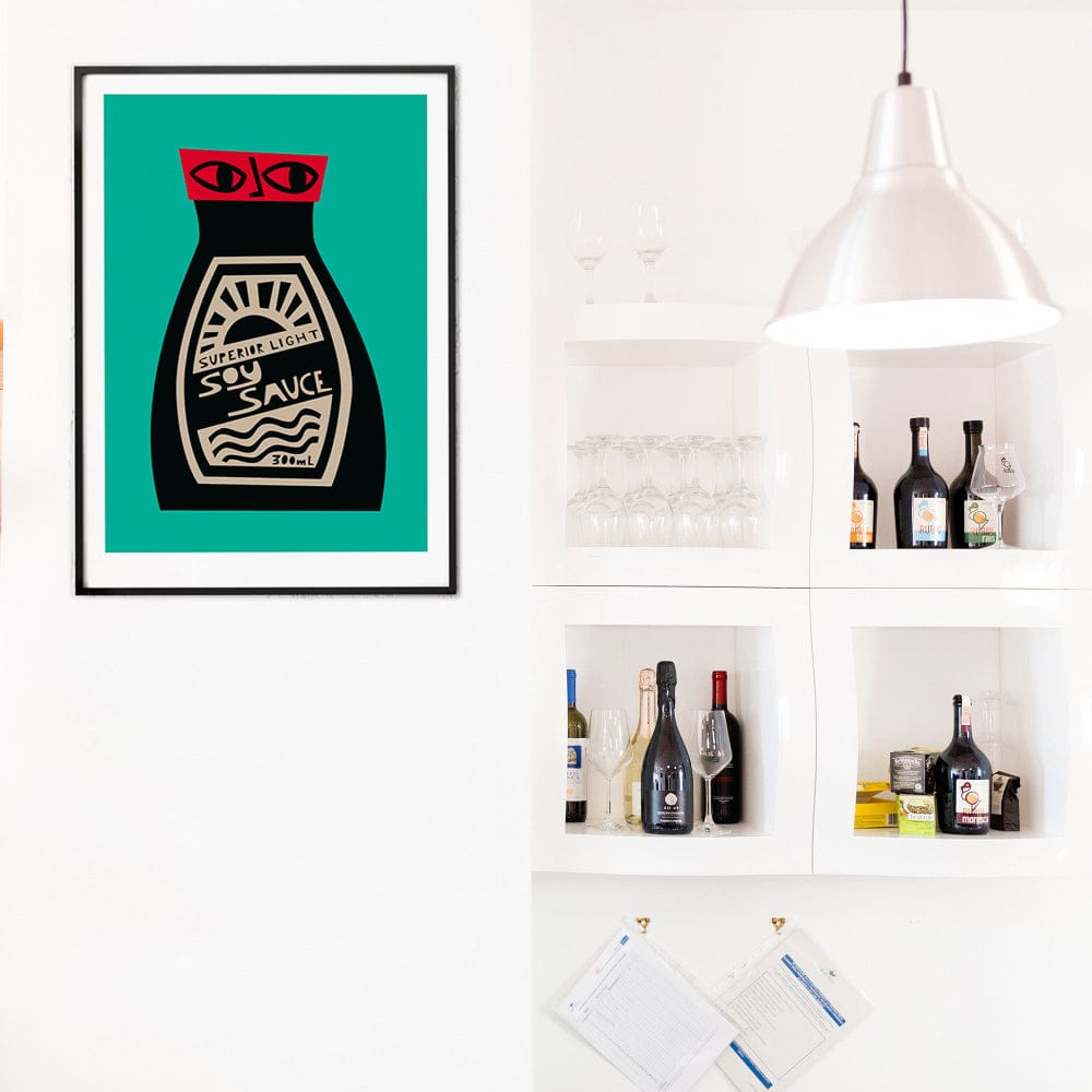 Soy Sauce poster framed above open shelving with bottles and barware in a bright white kitchen nook.