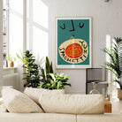 The Spaghetti Yum print on a teal wall in a sunlit living room, adding warmth and personality to the modern furnishings and leafy green decor.