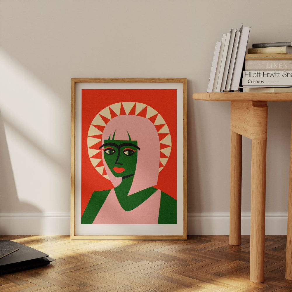 Sun halo portrait print leaning against wall next to wooden desk and stack of books