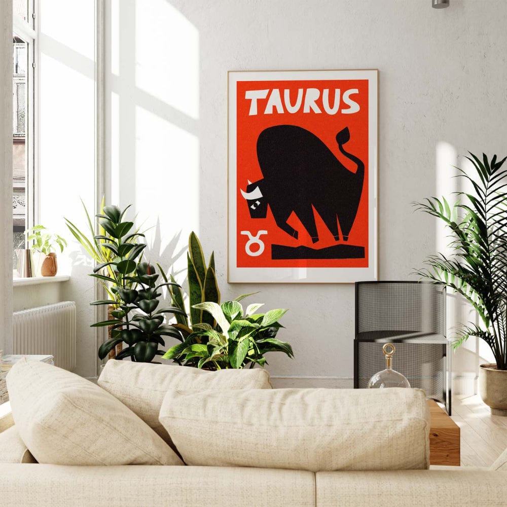 Taurus zodiac print framed in a bright living room with leafy plants and light wood furnishings.