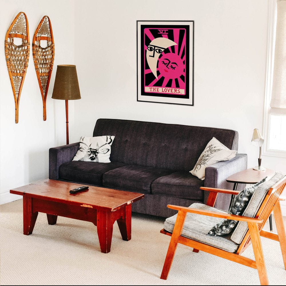 The Lovers tarot print hung above a retro sofa, paired with warm-toned furniture and wall-mounted snowshoes, creating an eclectic blend of modern mysticism and vintage charm.