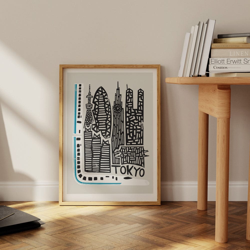 The Tokyo city print leaning against a wall beside a writing desk, its striking blue and black palette popping against the clean interior.