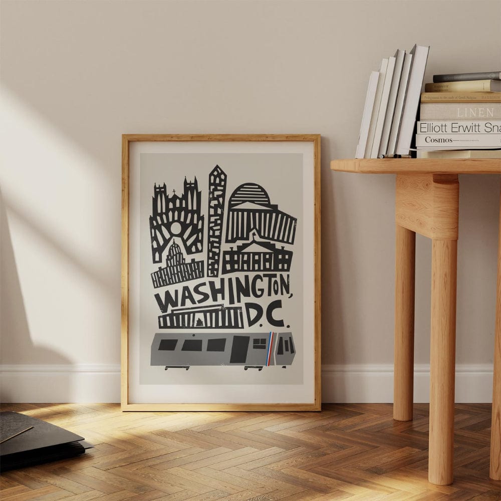 Washington D.C. city poster leaning against a wall in a reading nook with a wooden desk and sunlight casting soft shadows.