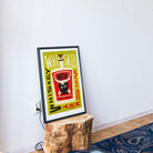 Whiskey poster resting casually against a white wall on a rustic tree stump base in a relaxed, boho interior.