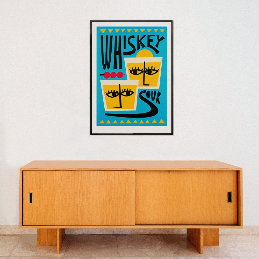 Whiskey Sour poster framed above light wood sideboard in a clean, modern interior space