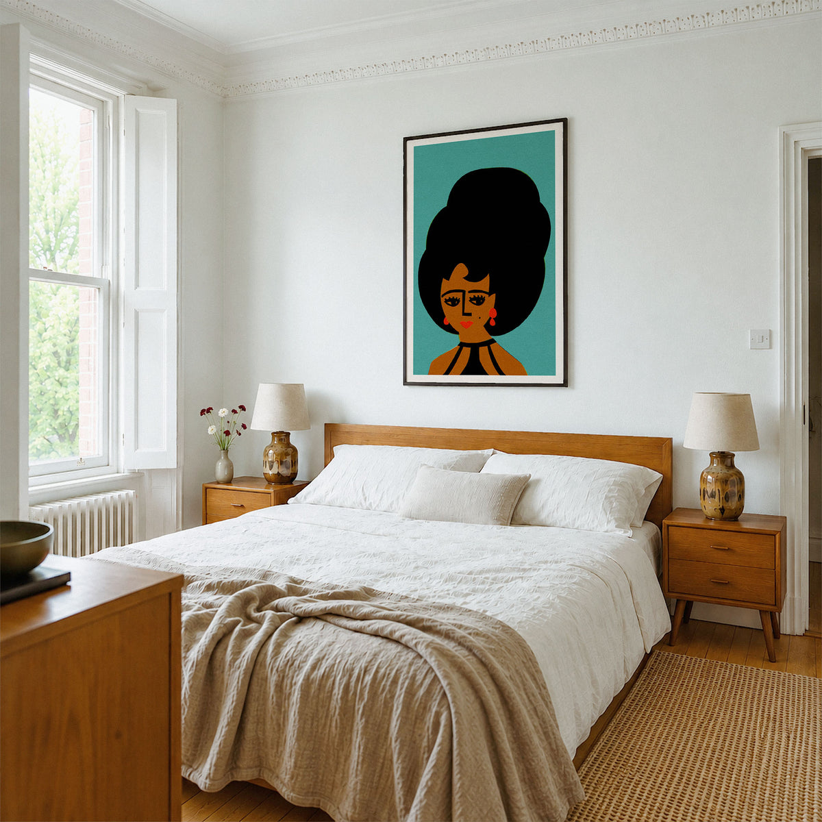 A framed art print featuring a retro-style illustration of a woman with a large black hair bun on a teal background, hanging on a white wall above a wooden bed in a bright, modern bedroom.