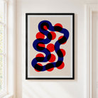 Framed abstract wall art hanging on a white wall beside a window. The print shows a wavy dark blue and black line with red circular dots on a light beige background, enclosed in a black frame with a white mat.
