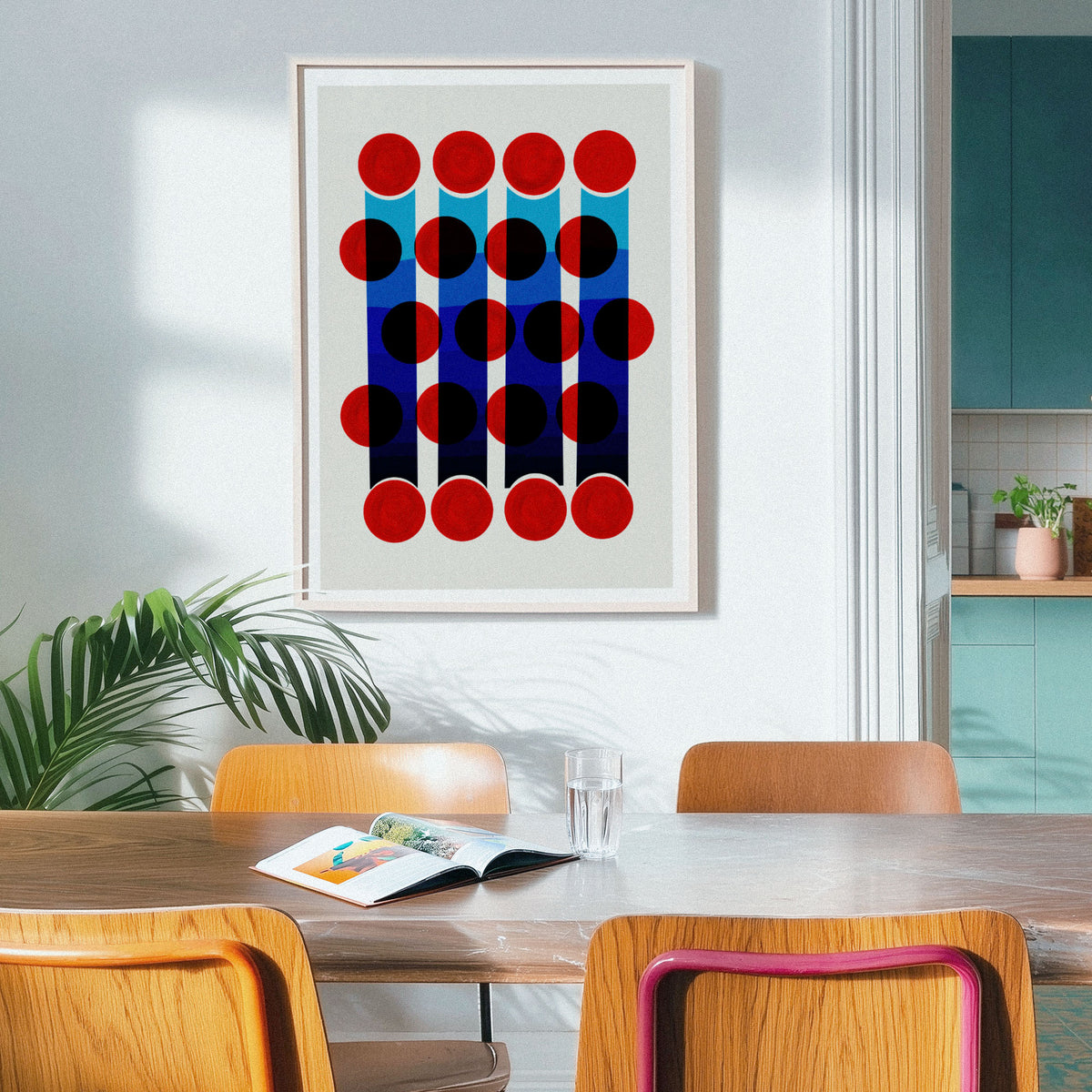 A framed art print featuring a retro-style with an abstract design of rectangles and circles, hanging on a light grey wall in a dining room setting with wooden chairs and a table.