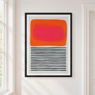 A framed abstract art print 'Sunset Ripples' hanging on a white wall in a bright room. The print features a large orange and pink rounded rectangle on the upper half and horizontal black stripes on the lower half, enclosed in a thin black frame.